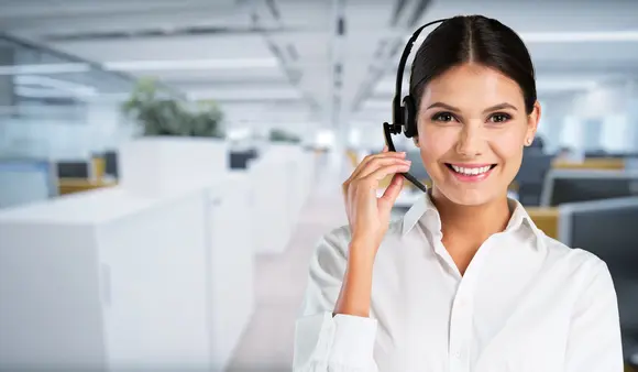 A smiling woman with a customer service headset in an office setting